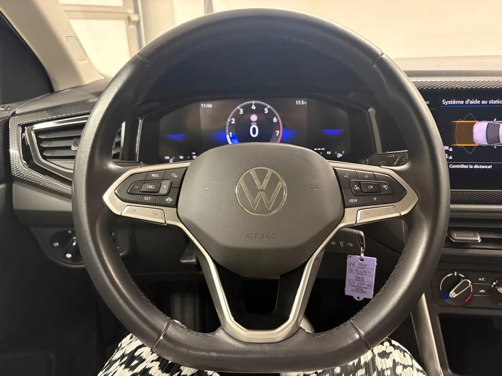 Vue rapprochée du volant noir de la Volkswagen Polo 2024 avec commandes intégrées et tableau de bord numérique allumé.