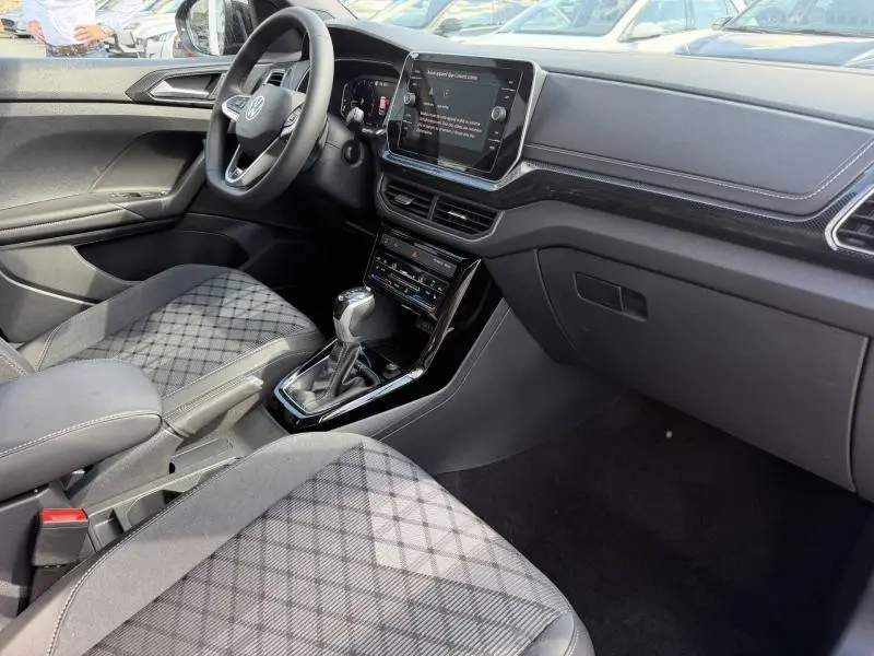 Vue intérieure côté conducteur du Volkswagen T-Cross 2026, finition R-Line, avec sièges tissu gris à motif et console centrale moderne.