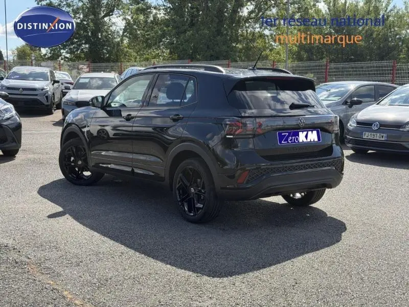 Vue 3/4 arrière droite d'un Volkswagen T-Cross noir avec jantes noires, sur un parking extérieur.