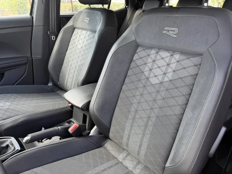 Vue rapprochée des sièges avant gris foncé avec logo R brodé, intérieur du Volkswagen T-Cross 2026 R-Line.