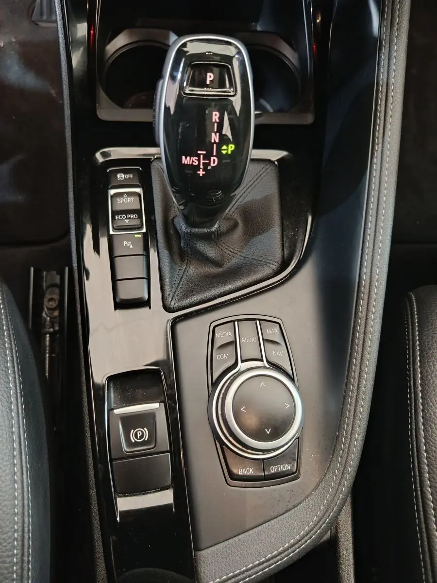 Gros plan sur la console centrale noire brillante du BMW X1 sDrive18i M Sport 2019 avec levier de vitesse automatique et molette de contrôle.