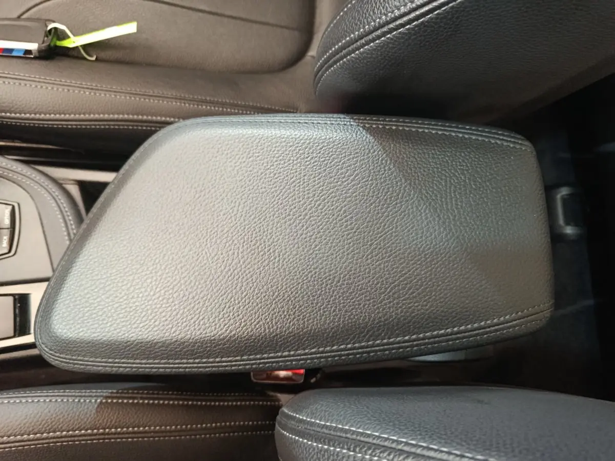Vue rapprochée de l'accoudoir central en cuir noir du BMW X1 sDrive18i M Sport 2019, avec coutures apparentes.