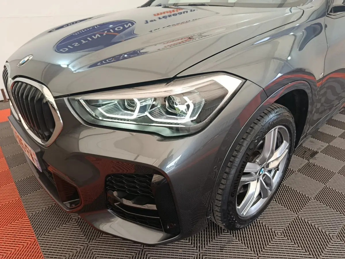 Gros plan sur l'avant droit gris métallisé du BMW X1 sDrive18i M Sport 2019 avec phares LED et jante alliage.