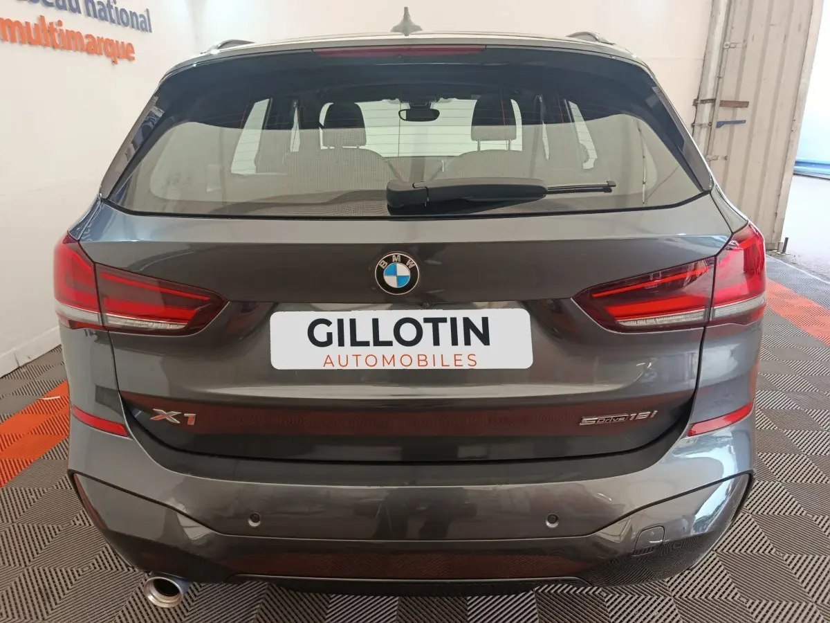 Vue arrière d'un BMW X1 sDrive18i M Sport gris métallisé avec feux LED et logo visible sur le hayon.