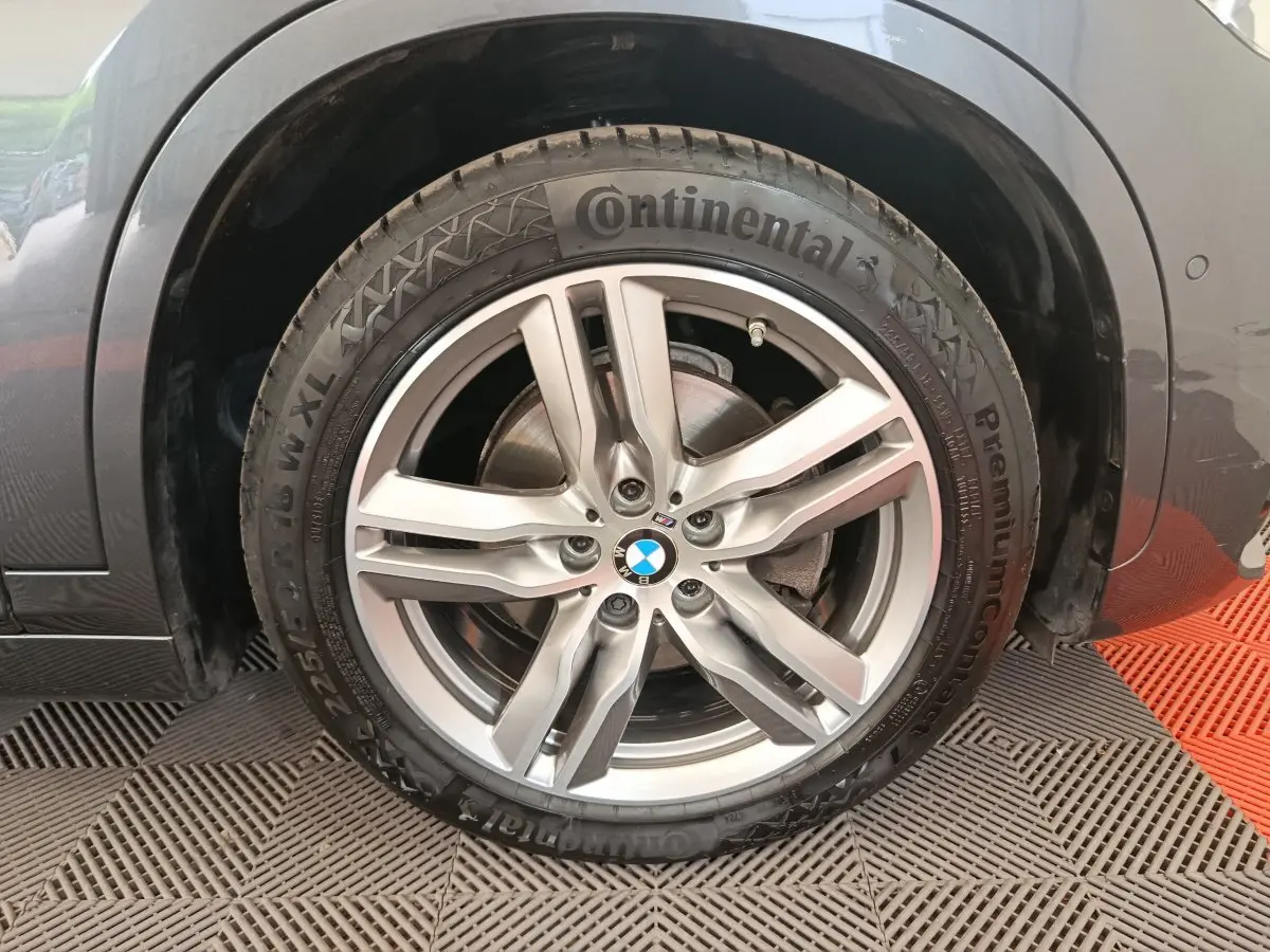 Gros plan sur la roue avant gauche d'un BMW X1 sDrive18i M Sport gris avec jante alliage et pneu Continental.
