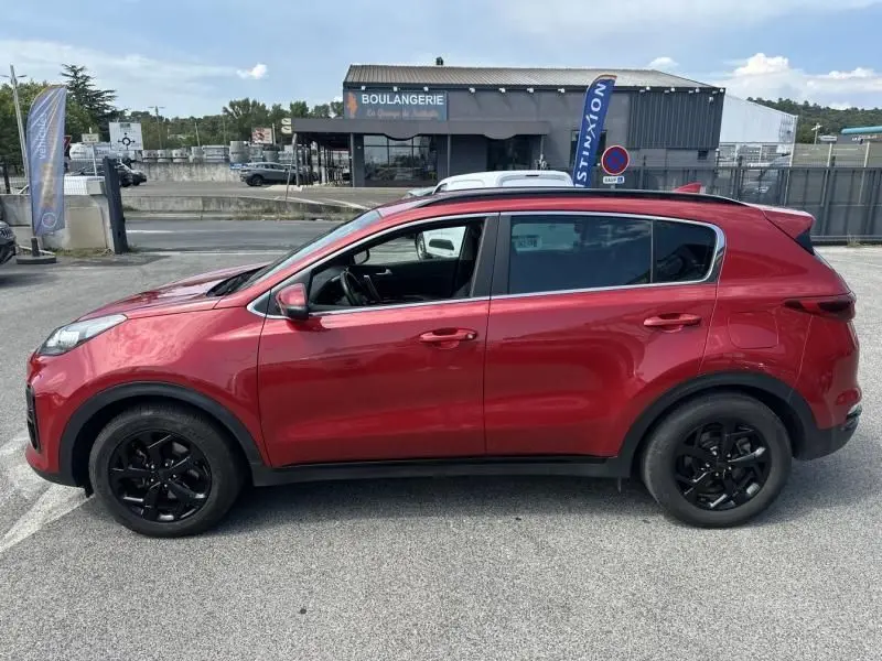 Profil côté gauche d'un KIA SPORTAGE rouge métal 2021 avec jantes noires et vitres teintées, version Black Edition.