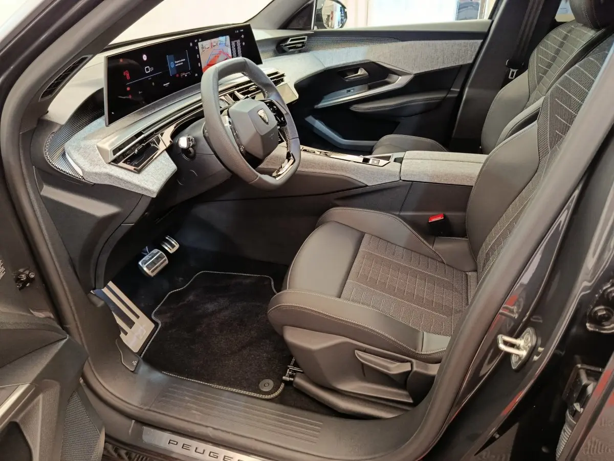 Intérieur avant droit du Peugeot 3008 blanc 2025, avec tableau de bord numérique et sièges en tissu gris.