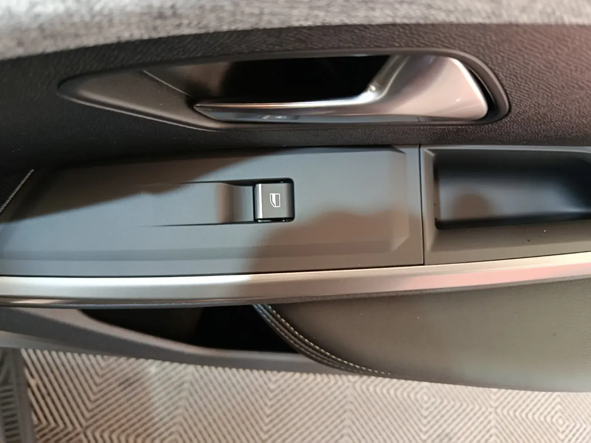 Détail de la commande de lève-vitre côté conducteur dans la porte intérieure noire du Peugeot 3008 blanc 2025.