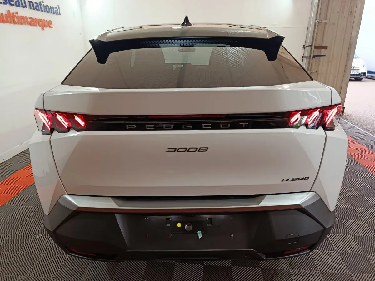 Vue arrière d'un Peugeot 3008 blanc hybride 2025 avec feux LED distinctifs allumés dans un garage.
