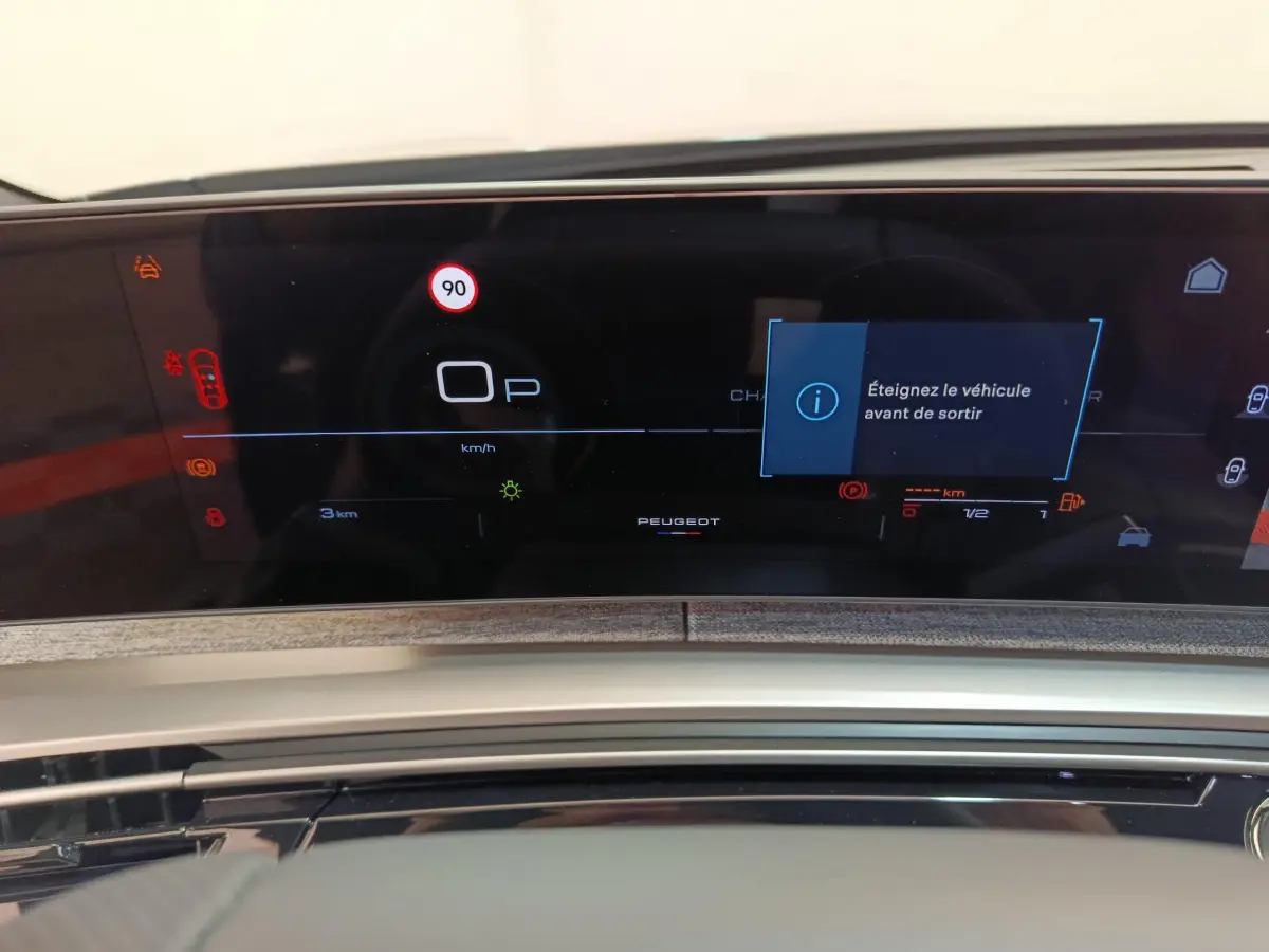 Tableau de bord numérique du Peugeot 3008 hybride 2025 affichant une alerte d'arrêt avant de sortir.
