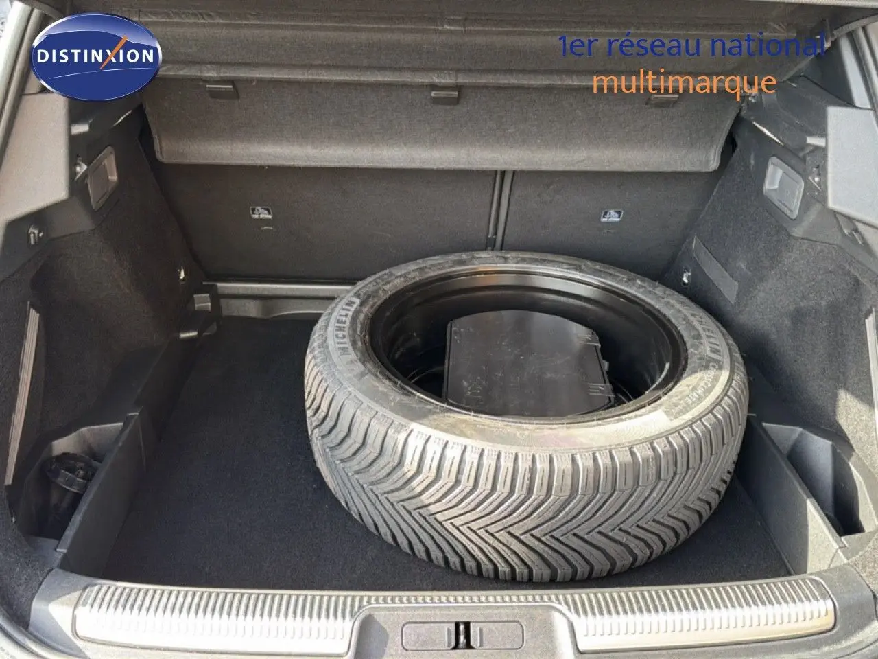 Coffre ouvert d’un DS7 1.5 BlueHDi 130 noir perle, vue plongeante sur la roue de secours et l’espace de rangement.