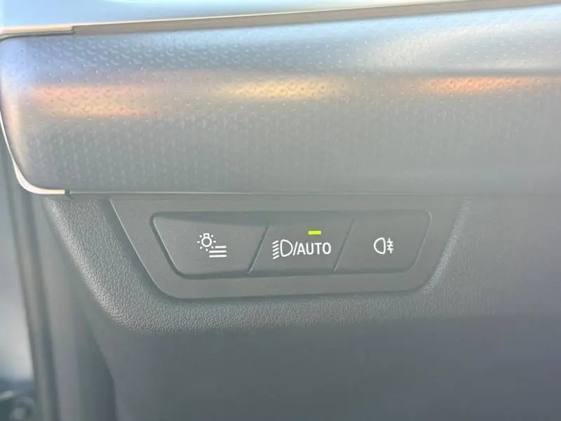Détail du tableau de bord d'une BMW X2 2025, montrant les commandes d'éclairage automatiques sur fond noir texturé.
