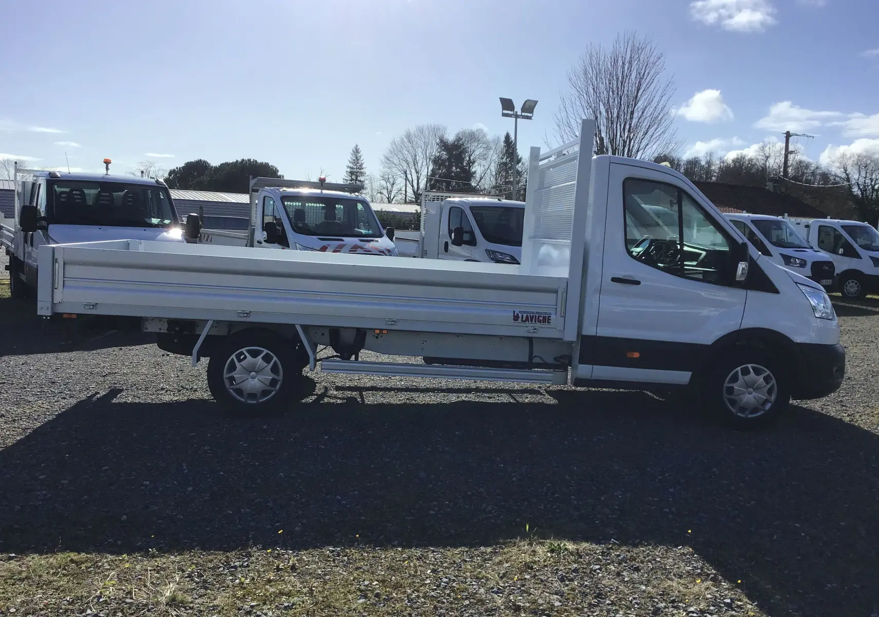 Ford Transit Chassis Cabine blanc vu de profil côté gauche avec plateau 4 mètres et ridelles aluminium.