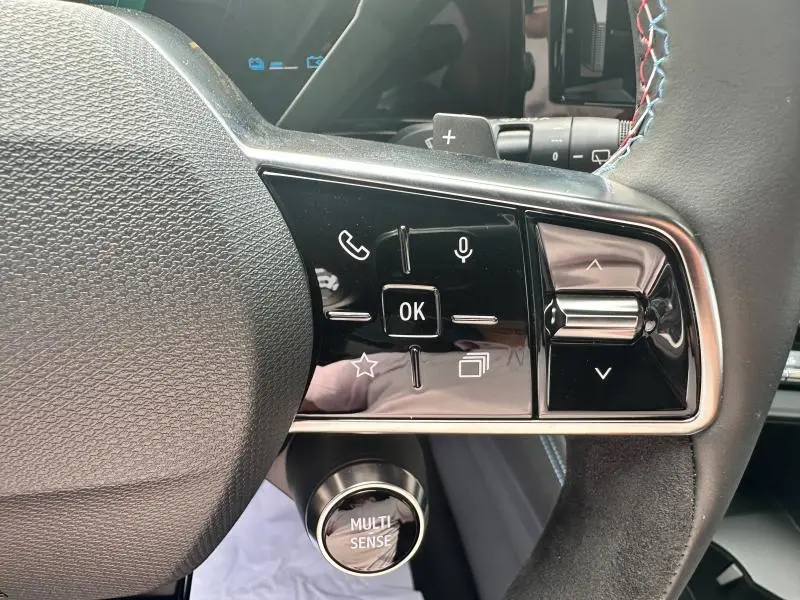 Gros plan sur les commandes au volant côté droit du Renault Austral gris, avec bouton Multi-Sense en dessous.