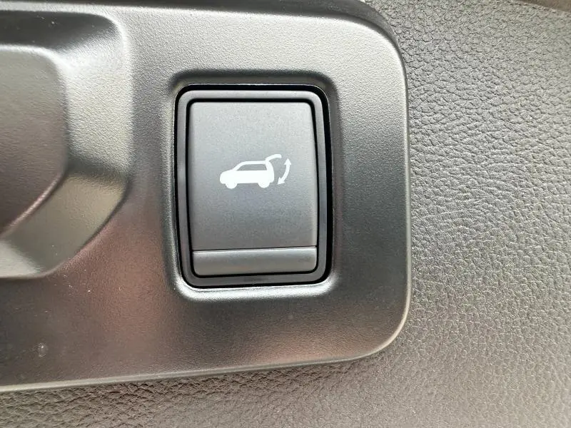 Bouton noir intérieur de Renault Austral 2025 gris, pour ouverture électrique du coffre, vue rapprochée.