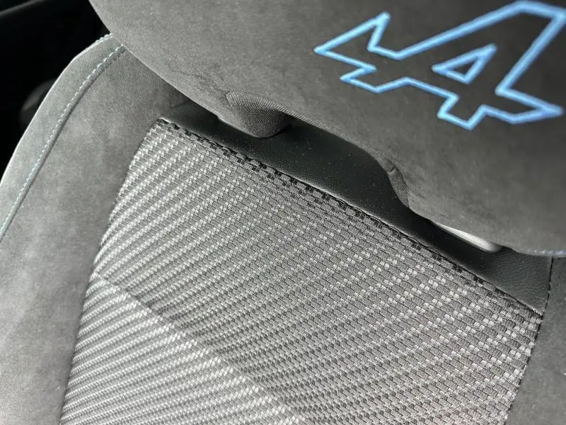 Gros plan sur l'assise en tissu carbone et Alcantara gris avec logo Alpine bleu sur appui-tête Renault Austral 2025.