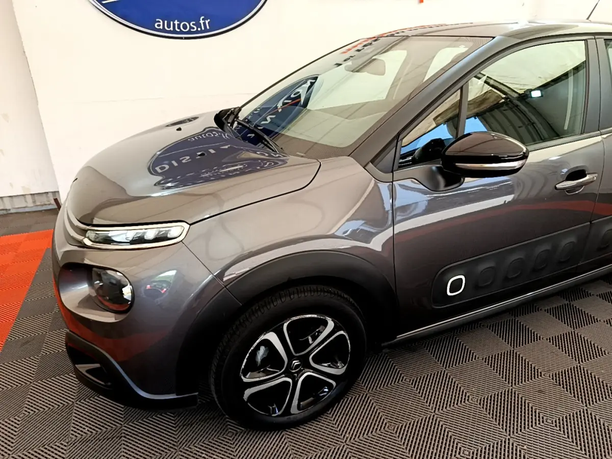 Vue 3/4 avant droit d'une Citroën C3 gris foncé avec jantes noires et inserts blancs sur les portières.