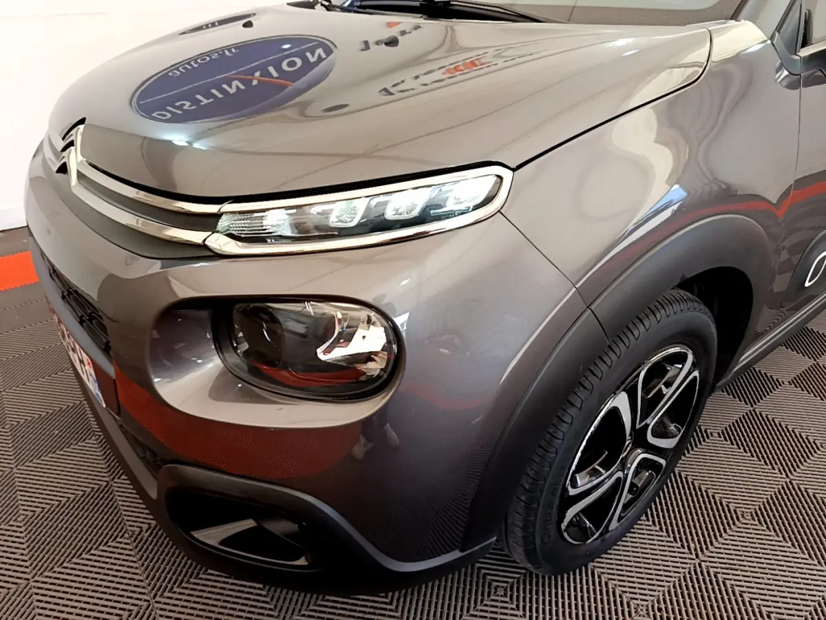 Vue 3/4 avant droit d'une Citroën C3 2019 gris foncé avec phares LED et jantes noires distinctives.