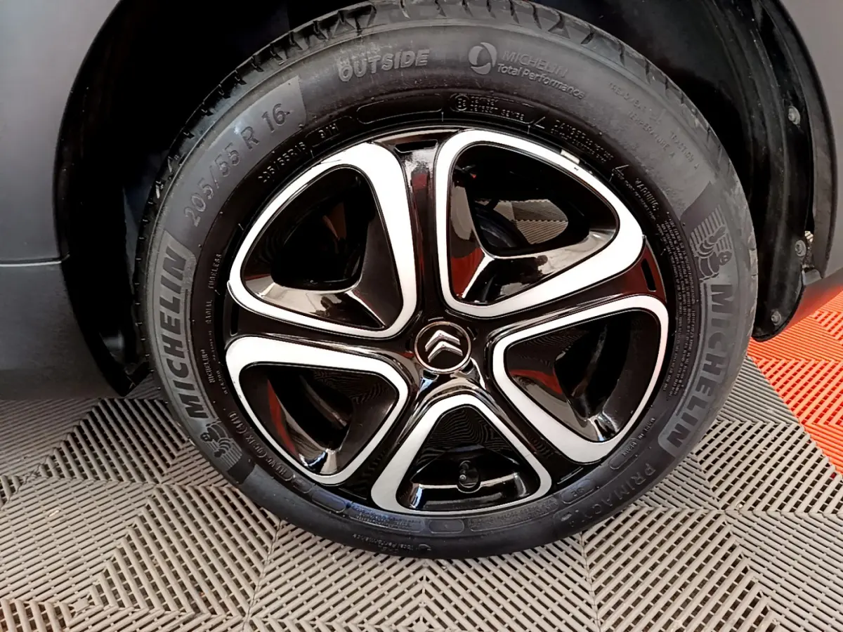 Gros plan sur la jante noire et argentée Michelin d'une Citroën C3 gris foncé, mettant en valeur le logo Citroën central.