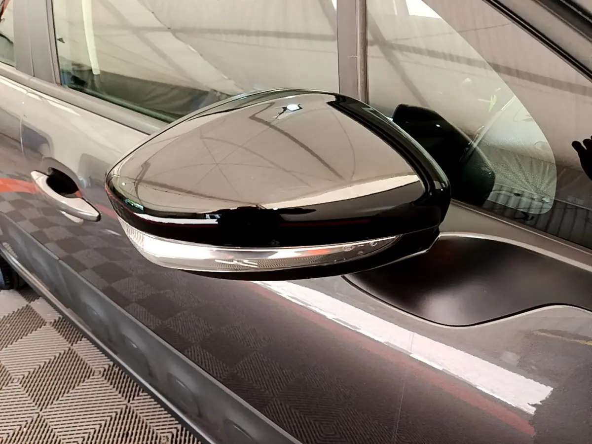Rétroviseur noir brillant côté gauche d'une Citroën C3 gris foncé vue de profil rapproché.
