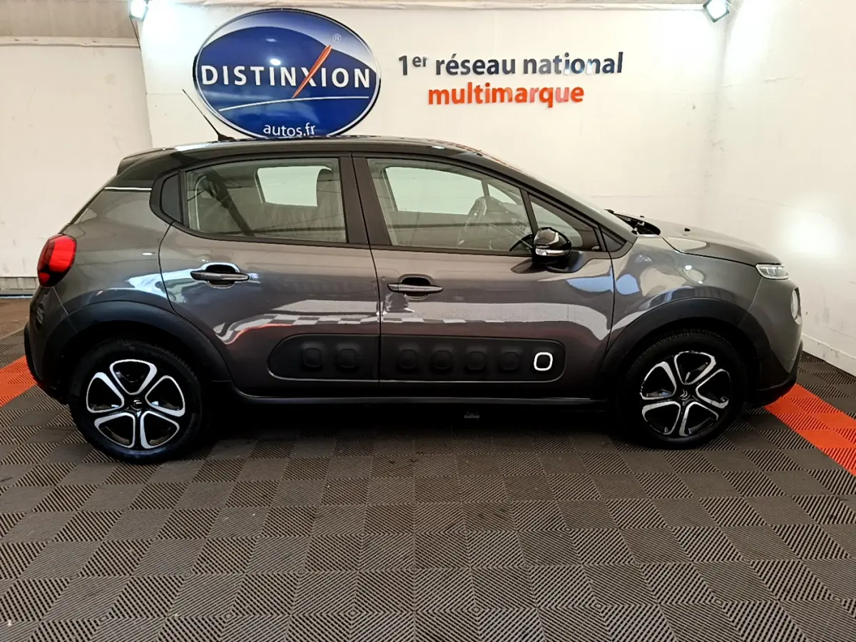 Profil côté droit d'une Citroën C3 gris foncé 2019 avec protections latérales noires et jantes stylisées.