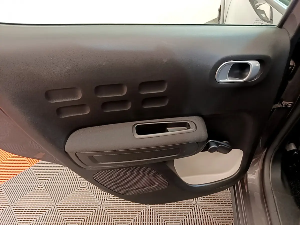 Vue intérieure du panneau de porte avant droit gris foncé de la Citroën C3 2019 avec poignée et commande manuelle de vitre