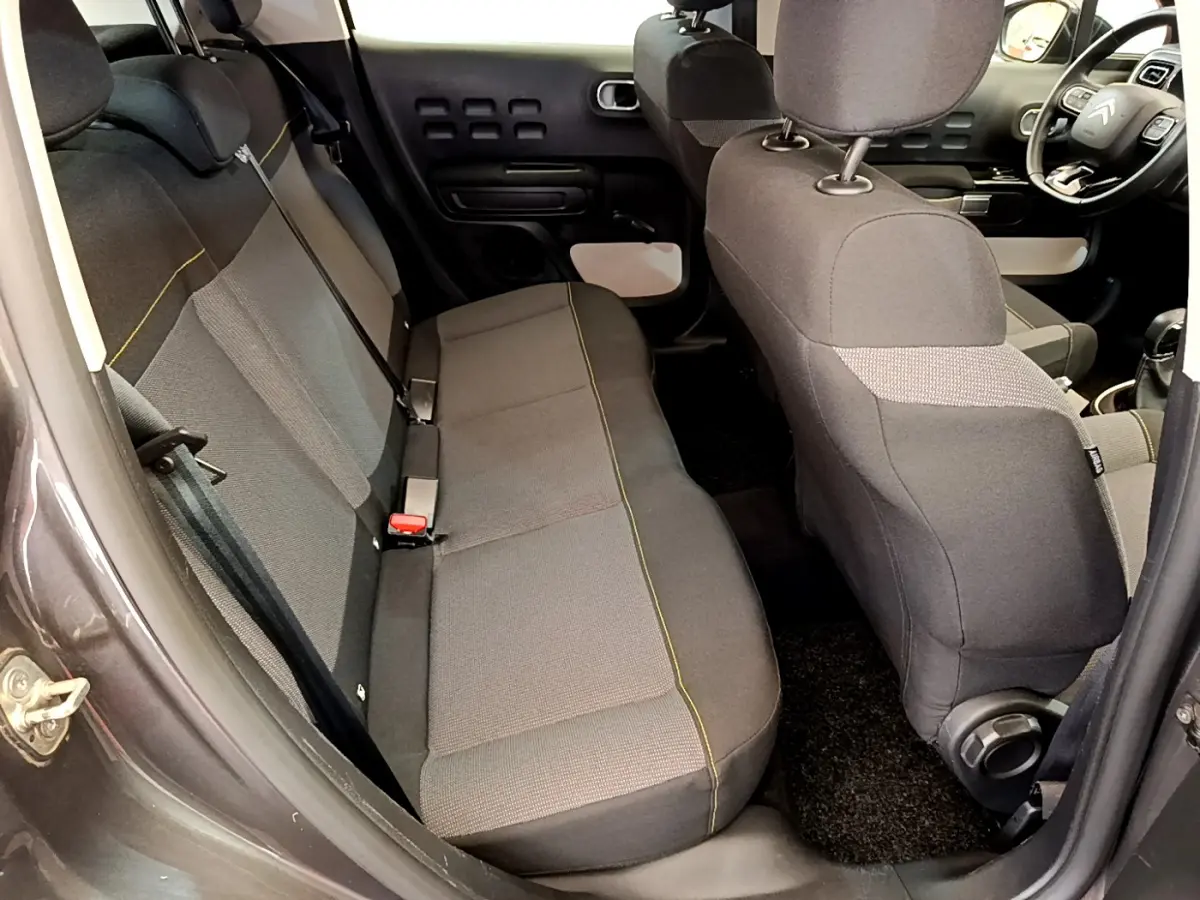 Vue intérieure côté gauche arrière de la Citroën C3 gris foncé, montrant la banquette arrière et l'avant du siège conducteur.
