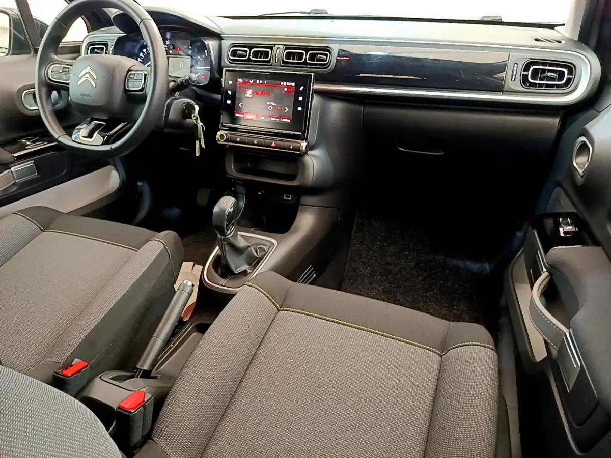 Intérieur de la Citroën C3 gris foncé, vue côté conducteur, tableau de bord avec écran tactile central et volant multifonctions cuir.