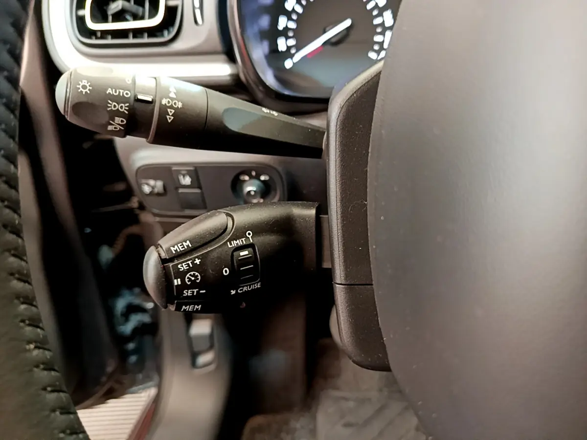 Gros plan sur le volant cuir et les commandes de régulateur de vitesse d'une Citroën C3 gris foncé, version Shine 2019.