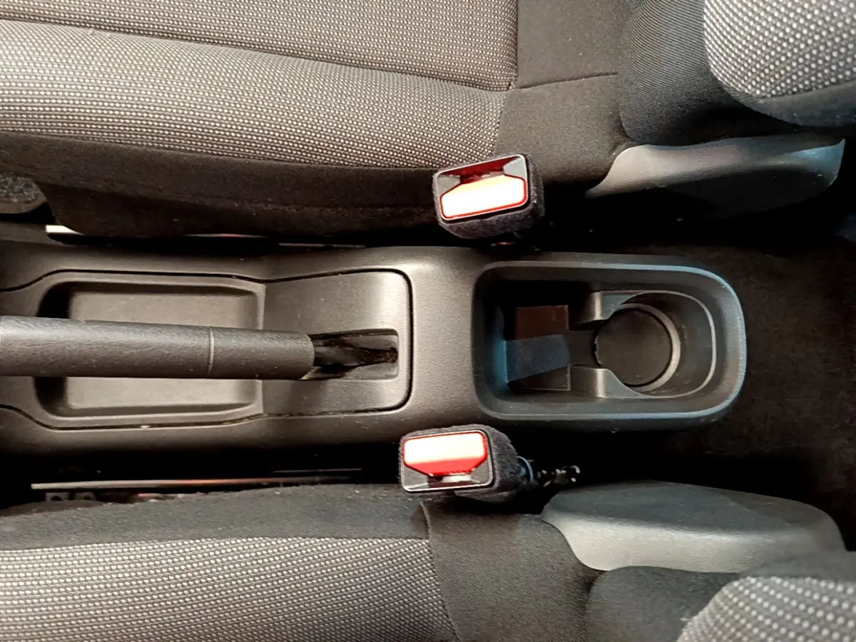 Vue plongeante sur la console centrale noire de la Citroën C3 2019, avec frein à main et porte-gobelet entre sièges gris foncé.