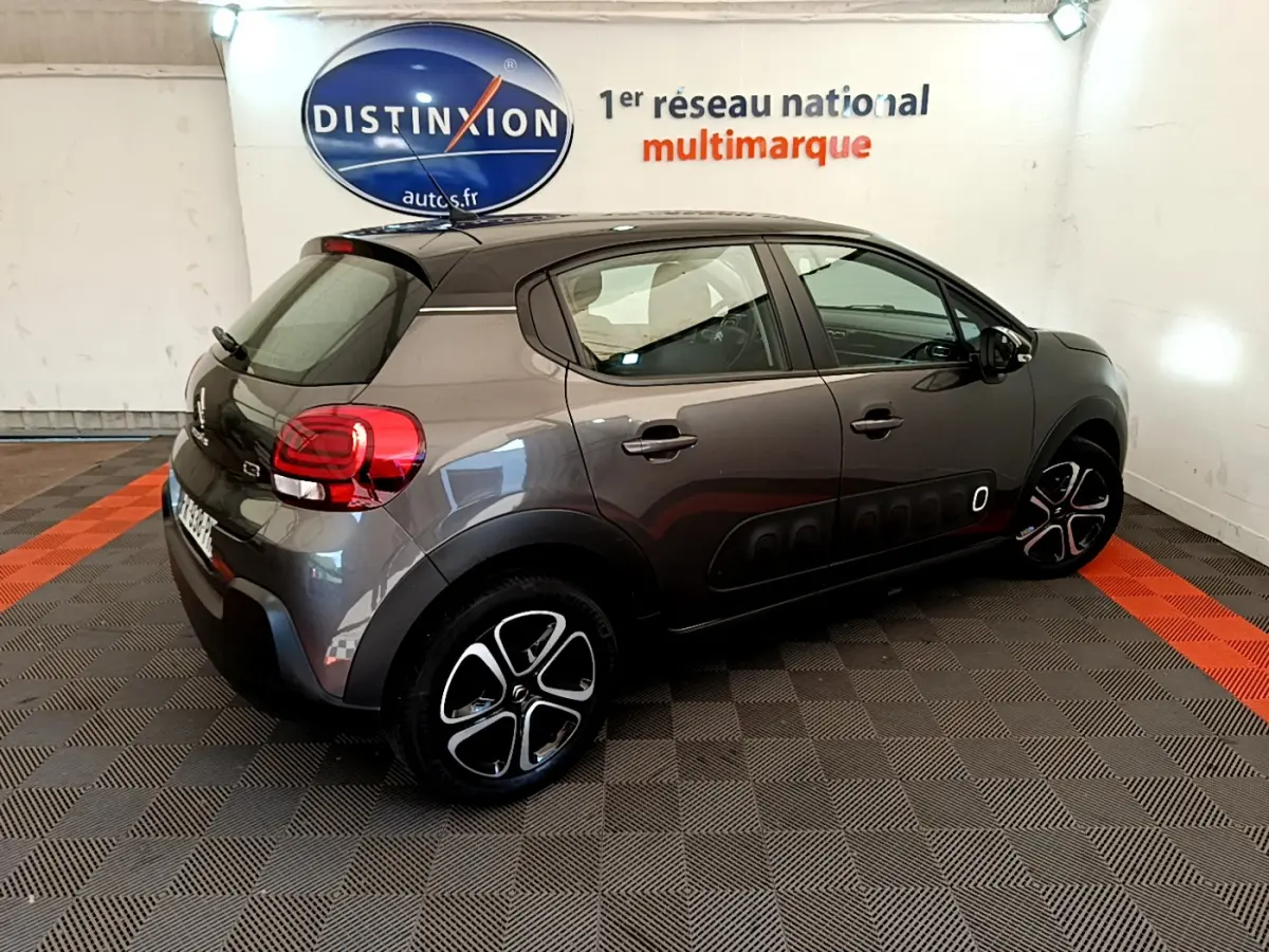 Citroën C3 gris foncé vue 3/4 arrière droit, avec protections latérales noires et jantes distinctives.