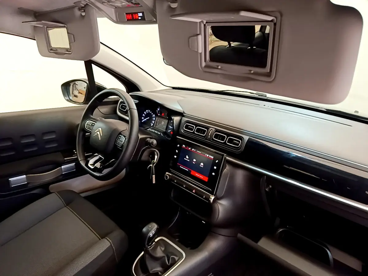Intérieur de la Citroën C3 2019 vu côté conducteur, tableau de bord noir avec écran tactile central et volant cuir.