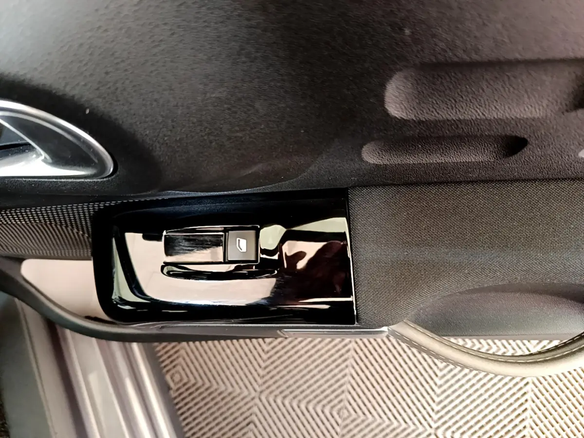 Détail de la commande de lève-vitre côté conducteur sur la porte intérieure noire d'une Citroën C3 gris foncé 2019.
