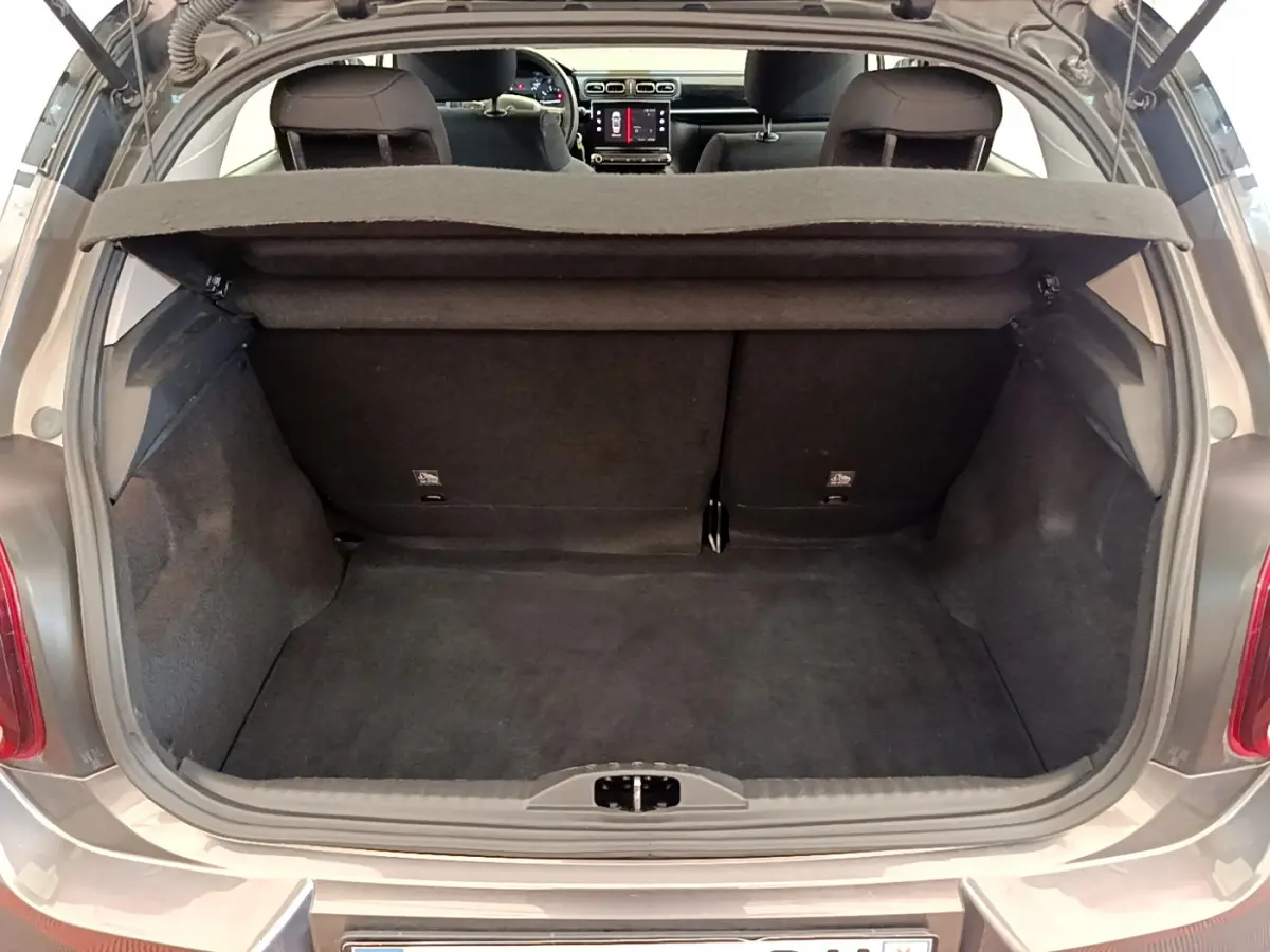 Coffre ouvert d'une Citroën C3 gris foncé vue de l'arrière, montrant l'espace de chargement et l'intérieur des sièges arrière.