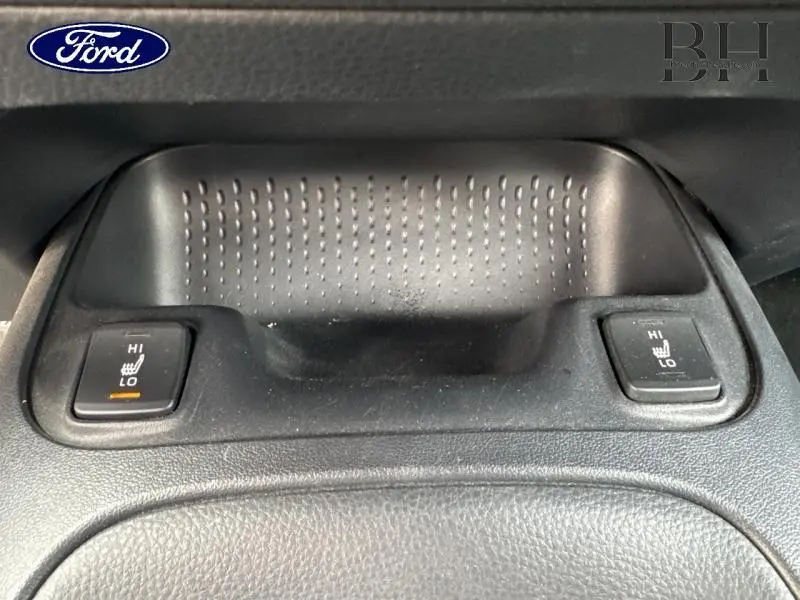 Gros plan sur les commandes de chauffage des sièges avant dans l'habitacle noir d'une Toyota Corolla gris Manhattan.