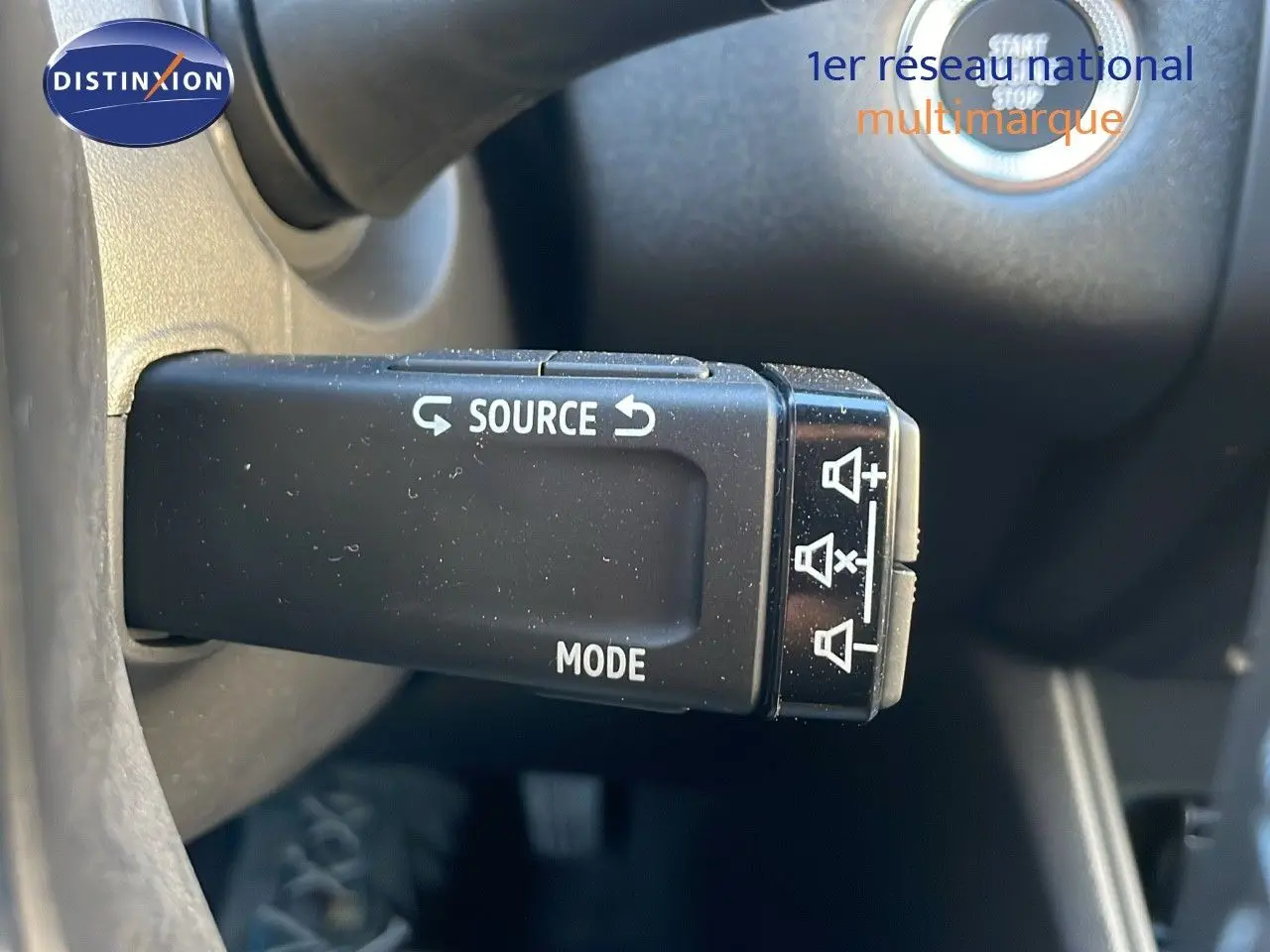 Gros plan sur la commande audio au volant du Renault Captur bleu iron metal 2025 avec toit noir.