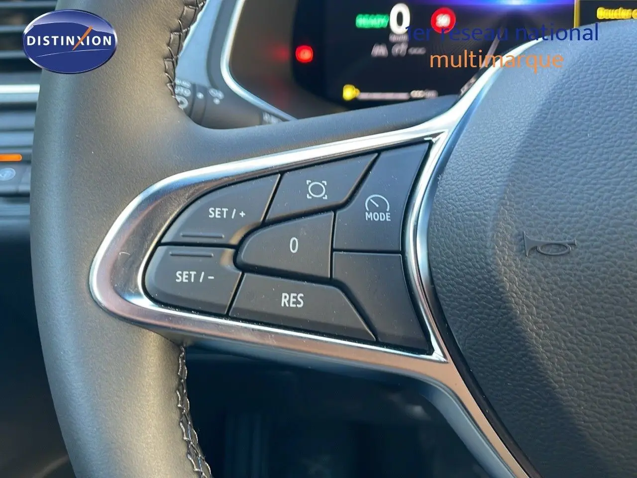 Gros plan sur les commandes au volant du Renault Captur E-Tech hybride 2025, avec tableau de bord numérique en arrière-plan.