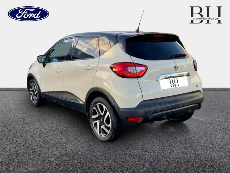 Vue 3/4 arrière droite d'un Renault Captur beige cendré avec toit noir étoilé et jantes alu distinctives.
