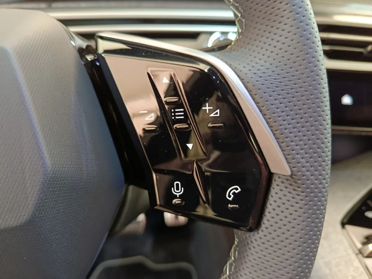 Gros plan sur les commandes tactiles noires du volant cuir perforé côté gauche du Peugeot 3008 1.2 Hybrid 145 GT noir.