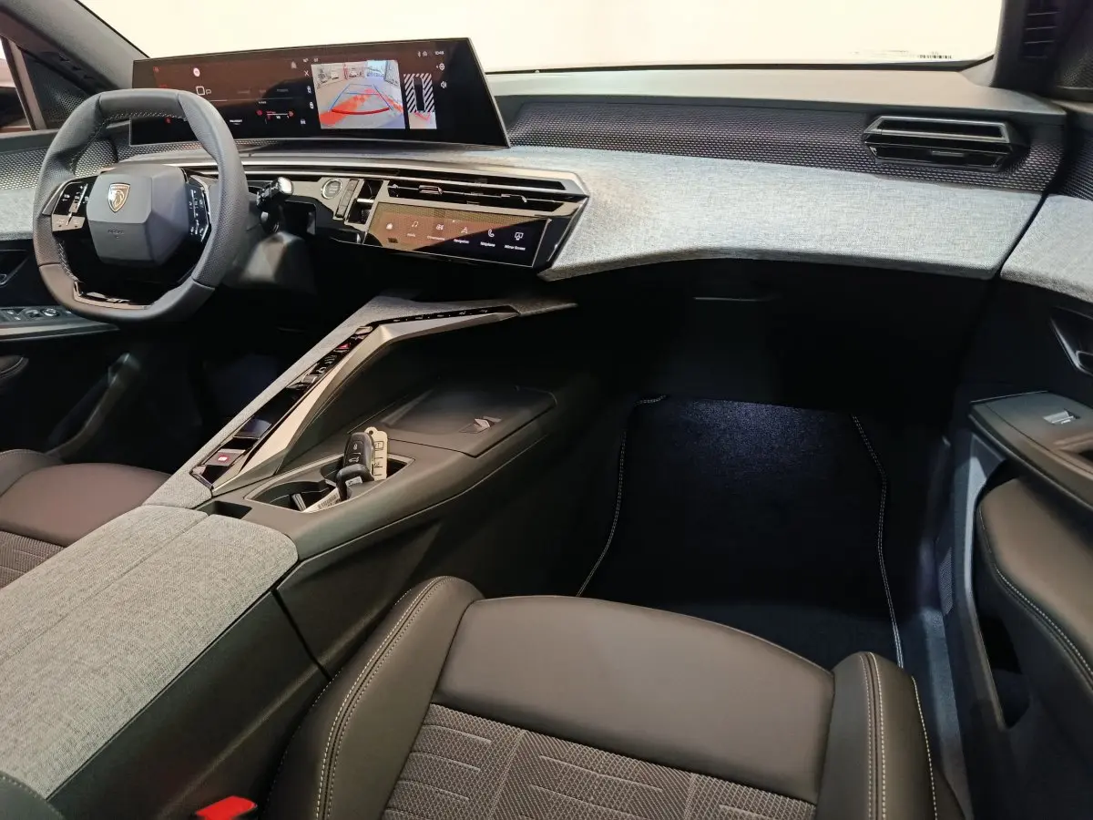 Intérieur du Peugeot 3008 2025 vu côté passager, tableau de bord moderne avec écran tactile large et sellerie grise et noire.