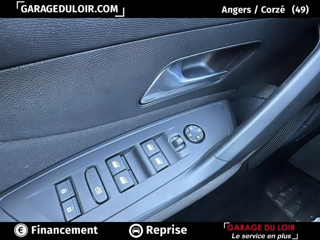 Gros plan sur la commande des vitres et rétroviseurs côté conducteur de la Peugeot 308 gris clair, intérieur noir.