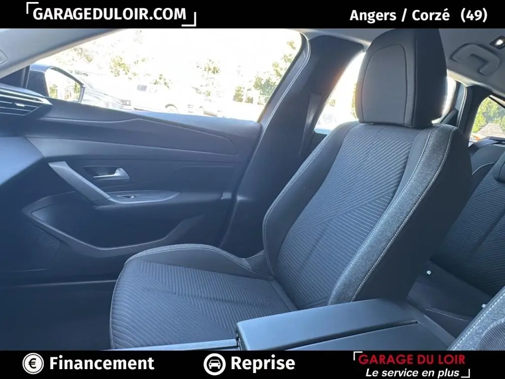 Intérieur de la Peugeot 308 2023, siège avant droit en tissu gris avec porte et tableau de bord côté droit visibles.