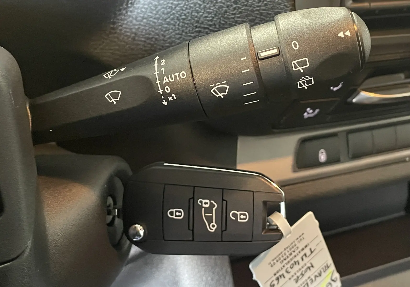 Gros plan sur la commande d’essuie-glace et la clé noire du Peugeot Traveller 2026 dans l’habitacle.