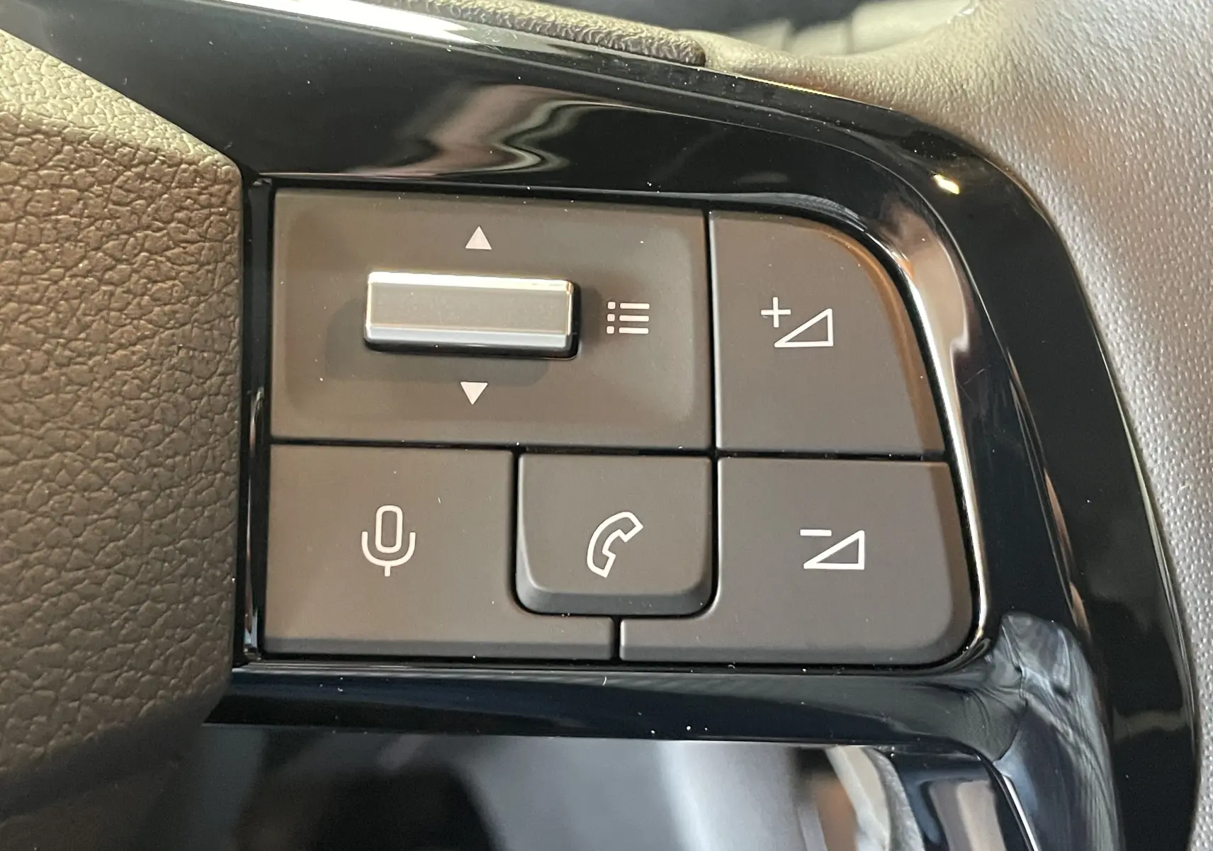 Gros plan sur les commandes au volant noir du Peugeot Traveller 2026, boutons de volume et téléphone visibles.