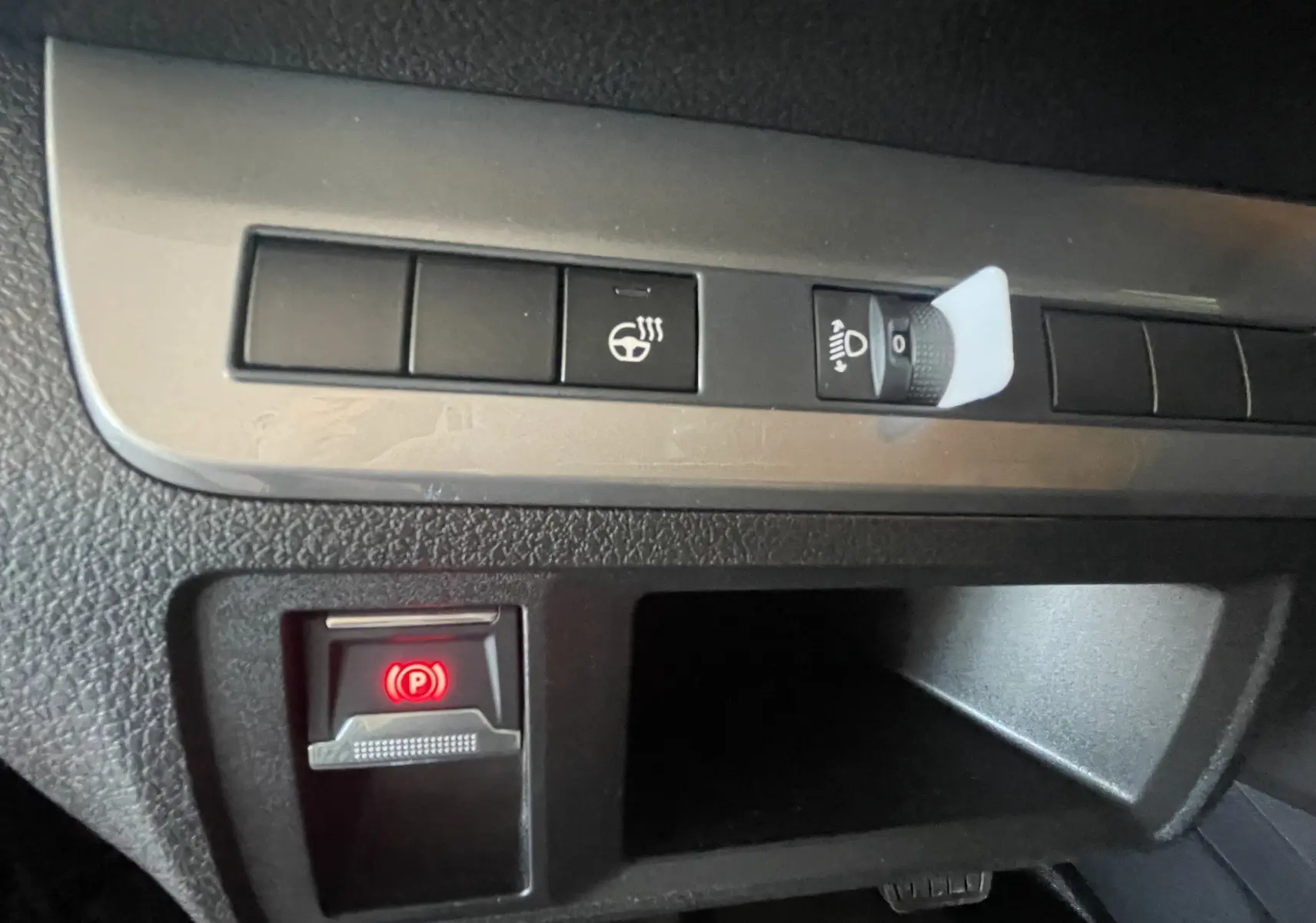 Gros plan sur les commandes intérieures du Peugeot Traveller noir, avec bouton de frein à main électronique éclairé en rouge.