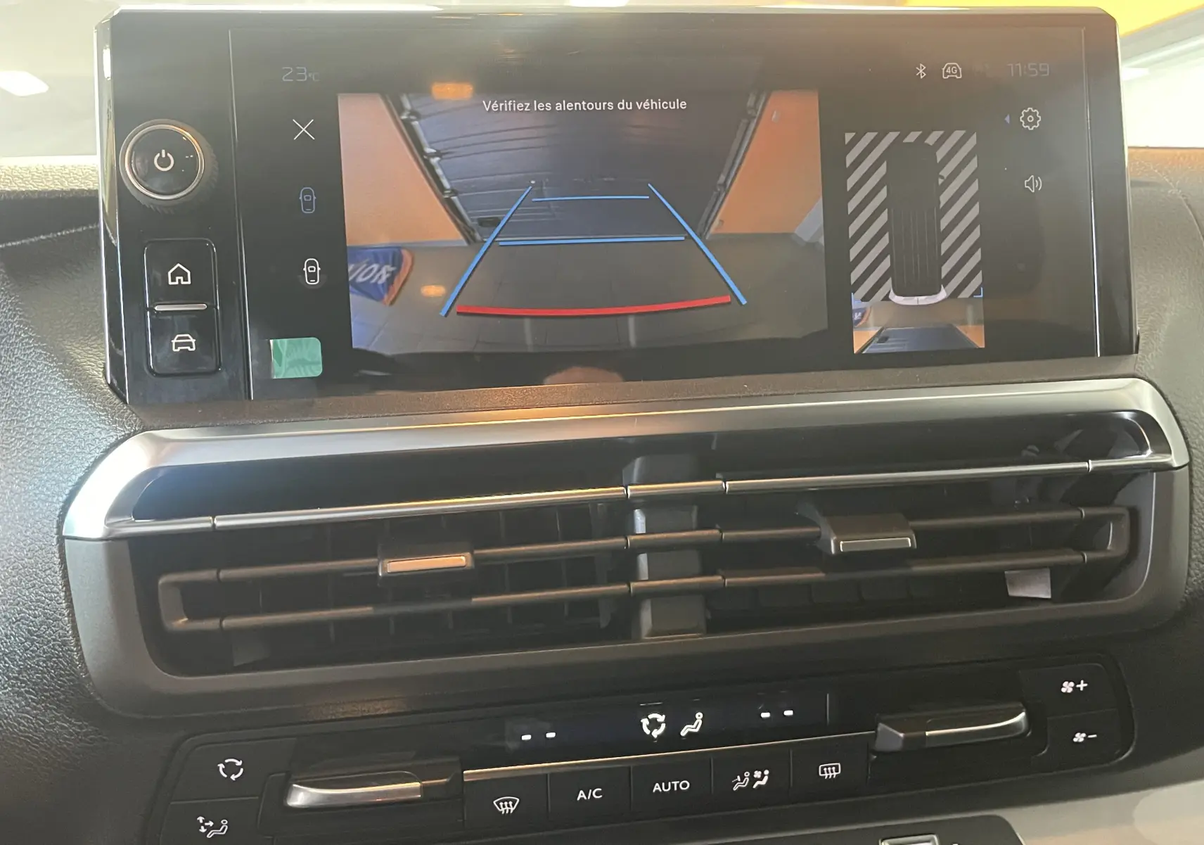 Vue rapprochée de l'écran tactile du Peugeot Traveller 2026 noir montrant la caméra de recul et les commandes de climatisation.