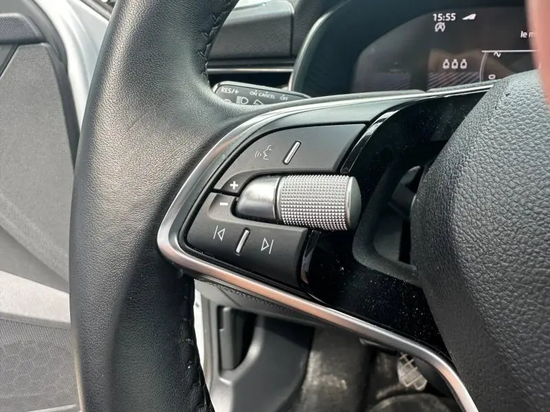 Gros plan sur les commandes au volant cuir noir du Skoda Scala gris argent 2025, côté gauche avec molette et boutons multifonctions.