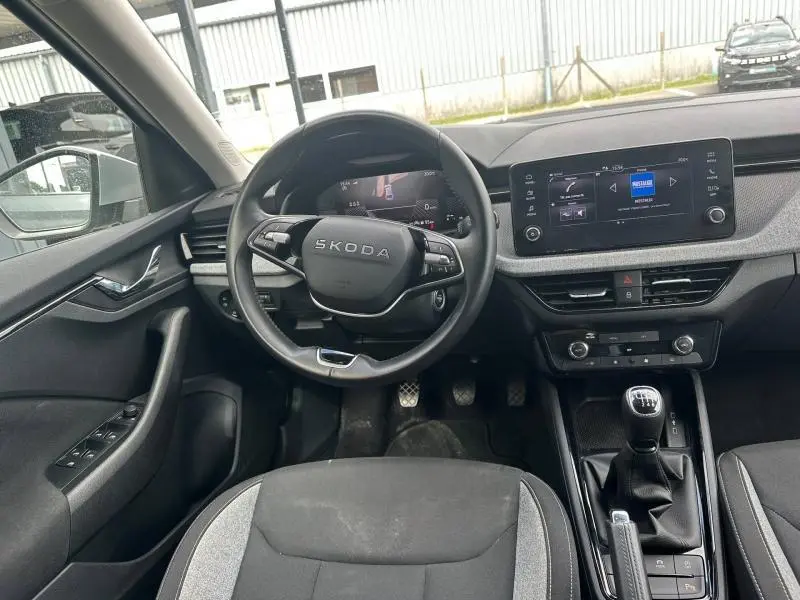 Vue intérieure avant de la Skoda Scala 2025, volant multifonction, écran tactile et levier de vitesses manuel noir.