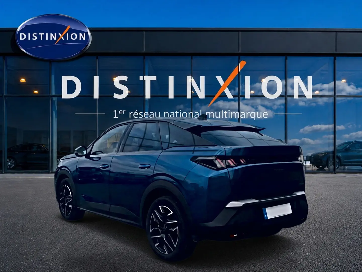 Peugeot 3008 bleu 3/4 arrière droit, avec jantes alu et feux arrière LED, devant un showroom Distinxion.