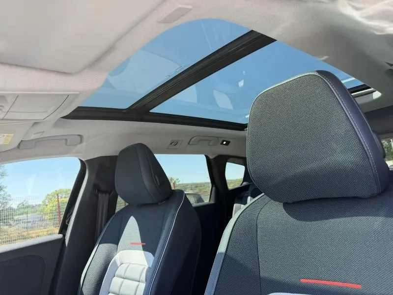 Intérieur du Citroën C5 Aircross 2026 noir, vue sur sièges avant et toit panoramique vitré sous lumière naturelle.